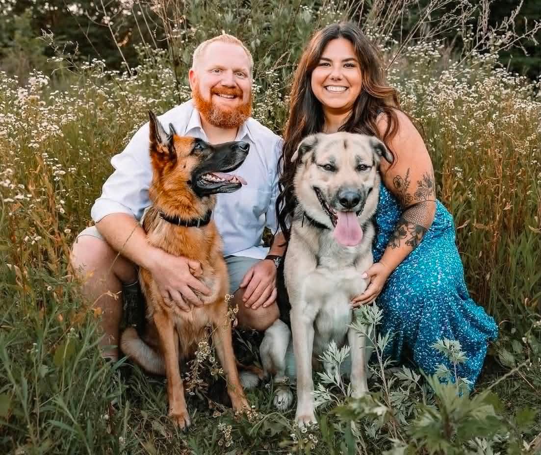 Brittany, owner of B's Customs, with her husband and two dogs in a wildflower field