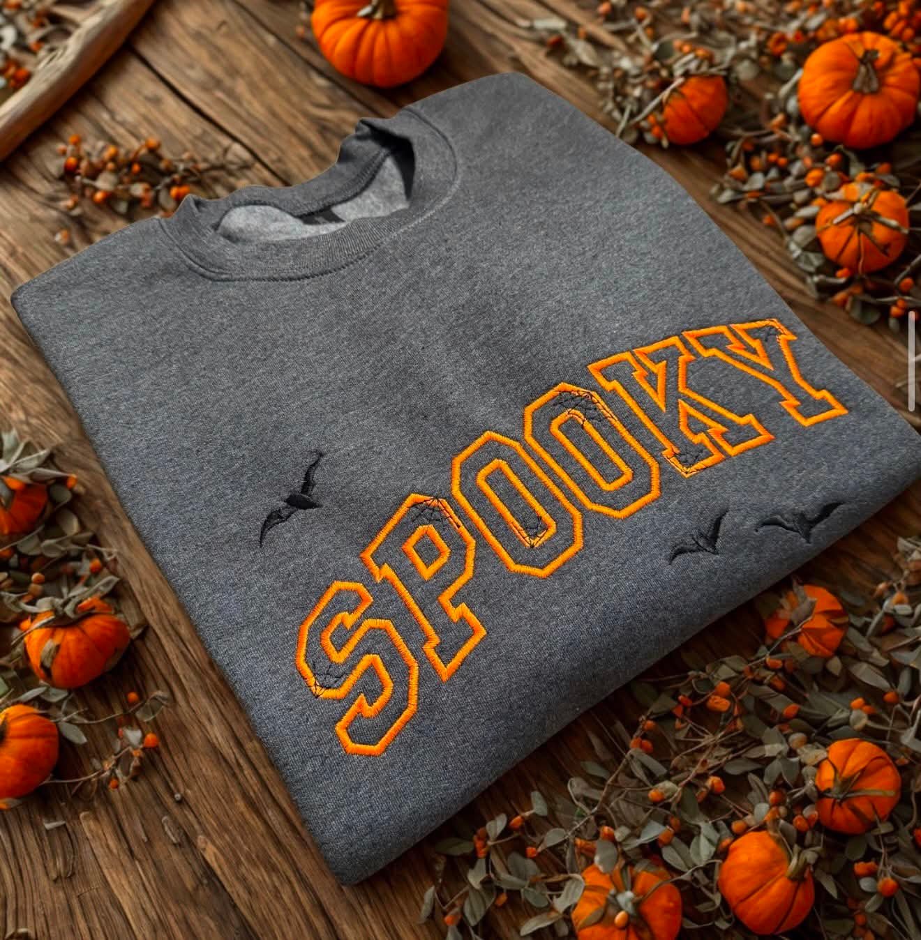 Heather grey crewneck embroidered with Spooky in orange lettering and bats for Halloween