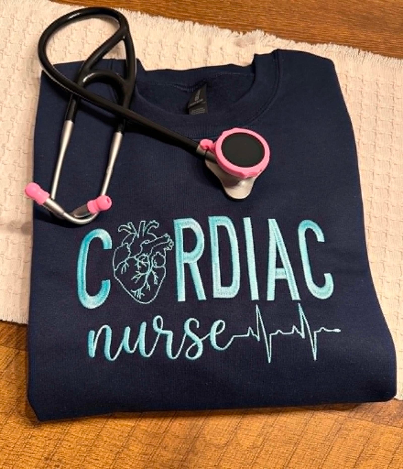 Navy Gildan crewneck embroidered with Cardiac Nurse, a heart illustration, and heartbeat line