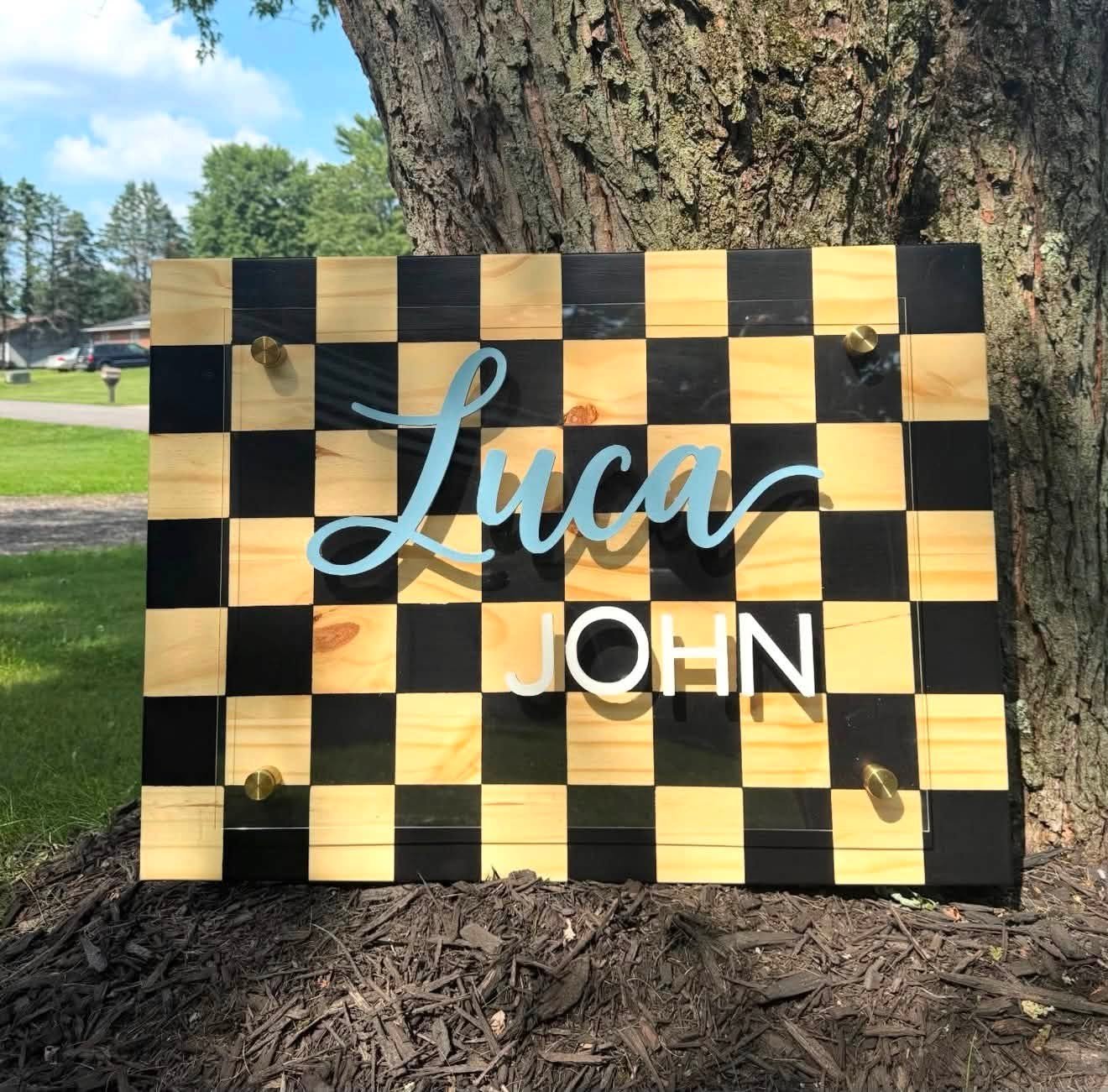 Checkerboard nursery name sign reading Luca John with acrylic overlay